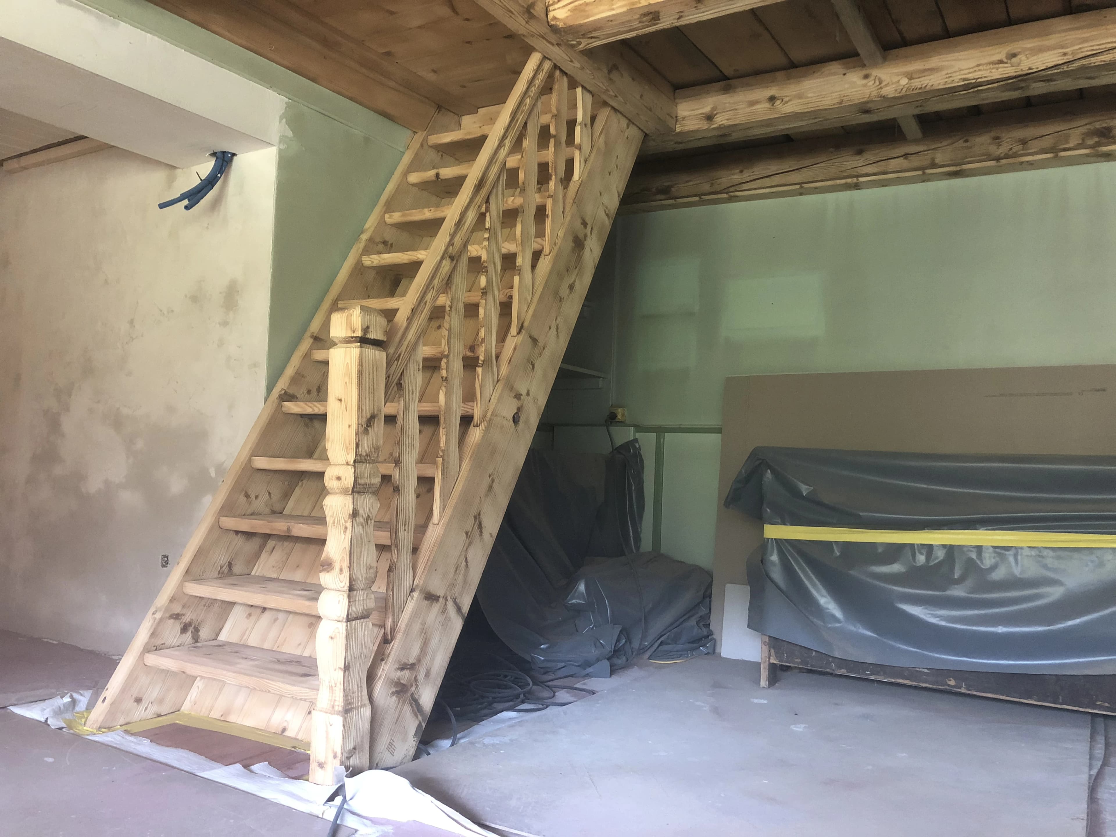 Poutres et escalier en bois sablés, meuble et sol encore sous bâches de protection